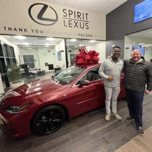 Customer posing with Salesmen with new Car