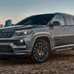 exterior view of a 2022 dark gray jeep compass with a city skyline in the background