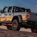 A Jeep Gladiator Mojave driving up a hill during a gorgeous sunset.