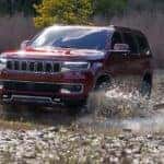 A red 2022 Jeep Wagoneer Series I drives through a small creek in the summertime!
