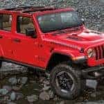 A red 2022 Jeep Wrangler Rubicon is parked in rocky terrain after off-roading.