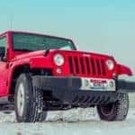 A red Jeep Wrangler parked on a snowpack. Image demonstrates what you could get with Jeep Incentives.