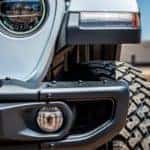 The grill of a Silver Jeep sits in the foreground. Image demonstrates one of the cars with high Jeep Safety Ratings.