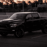 A black Ram 1500 is parked by a football field at sunset. Image demonstrates that there are Ram 1500 for sale.