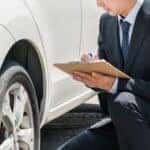 Salesman assessing car to make estimate