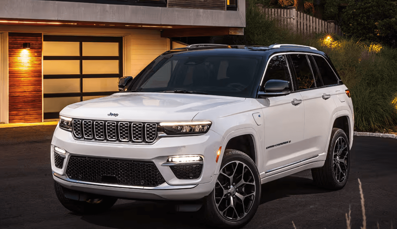 A white 2024 Jeep Grand Cherokee 4xe parked in a driveway in front of a house