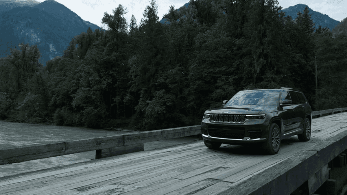 2024 Jeep Grand Cherokee driving across a bridge in the mountains
