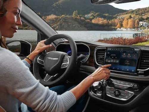 2023 Chrysler Pacifica PHEV view of woman adjusting audio on touchscreen display