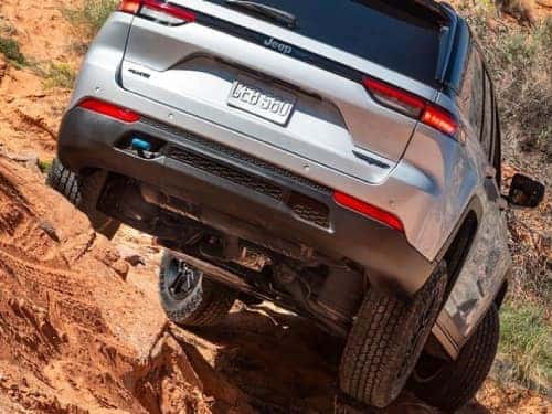 2024 Jeep Grand Cherokee 4xe rear exterior view of vehicle driving over rocky terrain