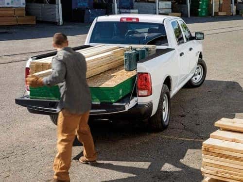 2024 RAM 1500 Classic view of man loading lumber into bed of truck