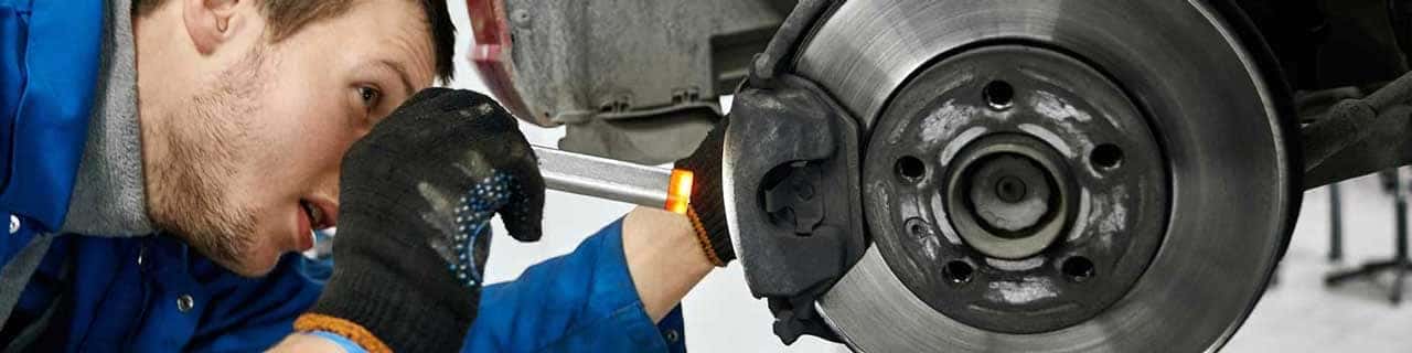 Close up view of a service tech inspecting a brake pad on a vehicle