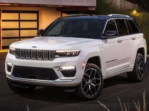 2025 Jeep Grand Cherokee parked outside a modern home at night