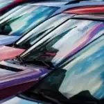 A row of cars in a used car lot, from windshield-level.