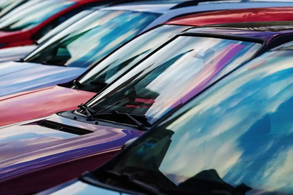 A row of cars in a used car lot, from windshield-level.